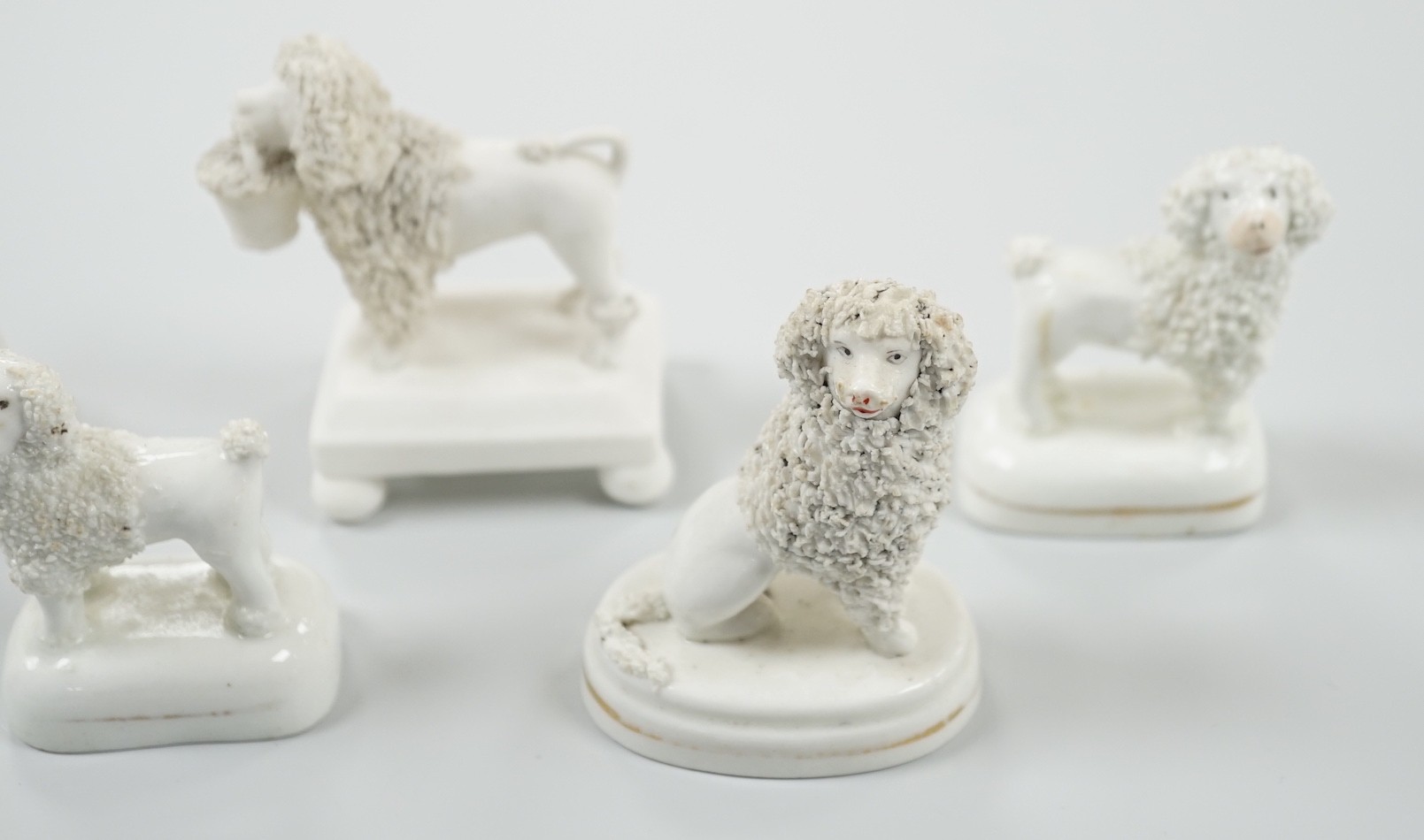 Five small Staffordshire models of poodles, together with a small poodle lying recumbent on an oval mounted base, possibly Davenport, c.1830-50, (6). Tallest 6.8cm., Provence: Dennis G. Rice collection, Cf. Dennis G.Rice